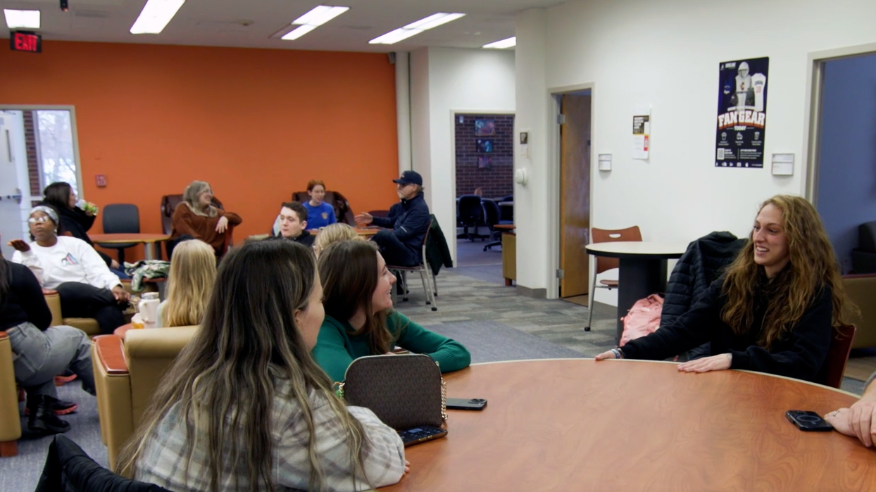 Several students sitting down together having conversations in a lobby-type area